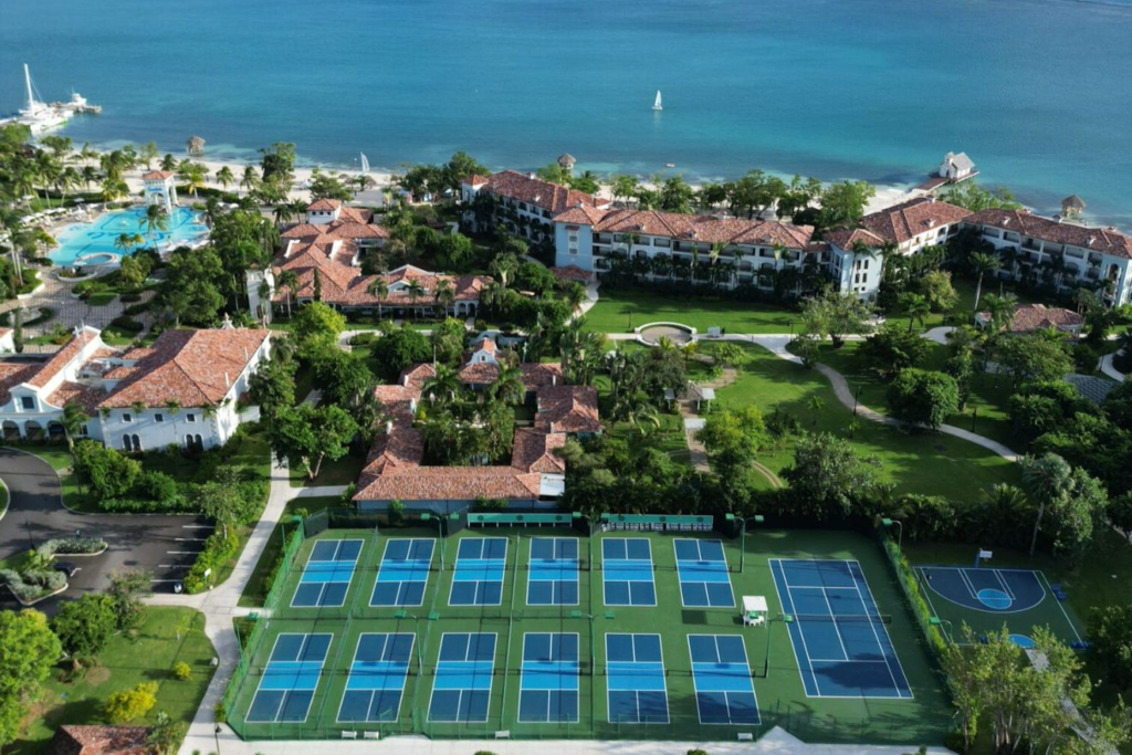 Aerial view of pickleball courts at Sandals South Coast with the Caribbean Sea and resort grounds in the background